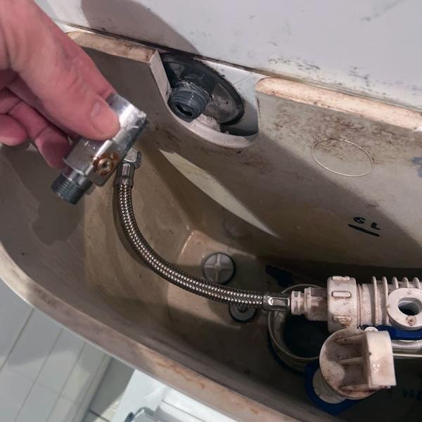 Toilet tank plumbing components being repaired